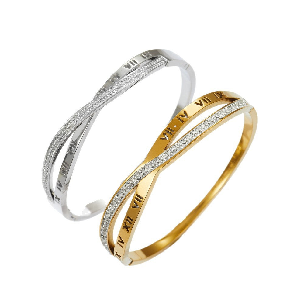 Engraved Roman numeral and pave cubic zirconia crossover stainless steel bangle bracelet jewelry in waterproof 18k gold plated finish.