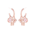 Rose gold huggie hoop earrings featuring a sparkling zirconia pave and a delicate four-leaf clover charm