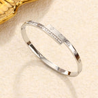 Engraved screw motif and channel-set cubic zirconia T-bar hinged cuff bangle in waterproof 18k gold plated stainless steel jewelry.