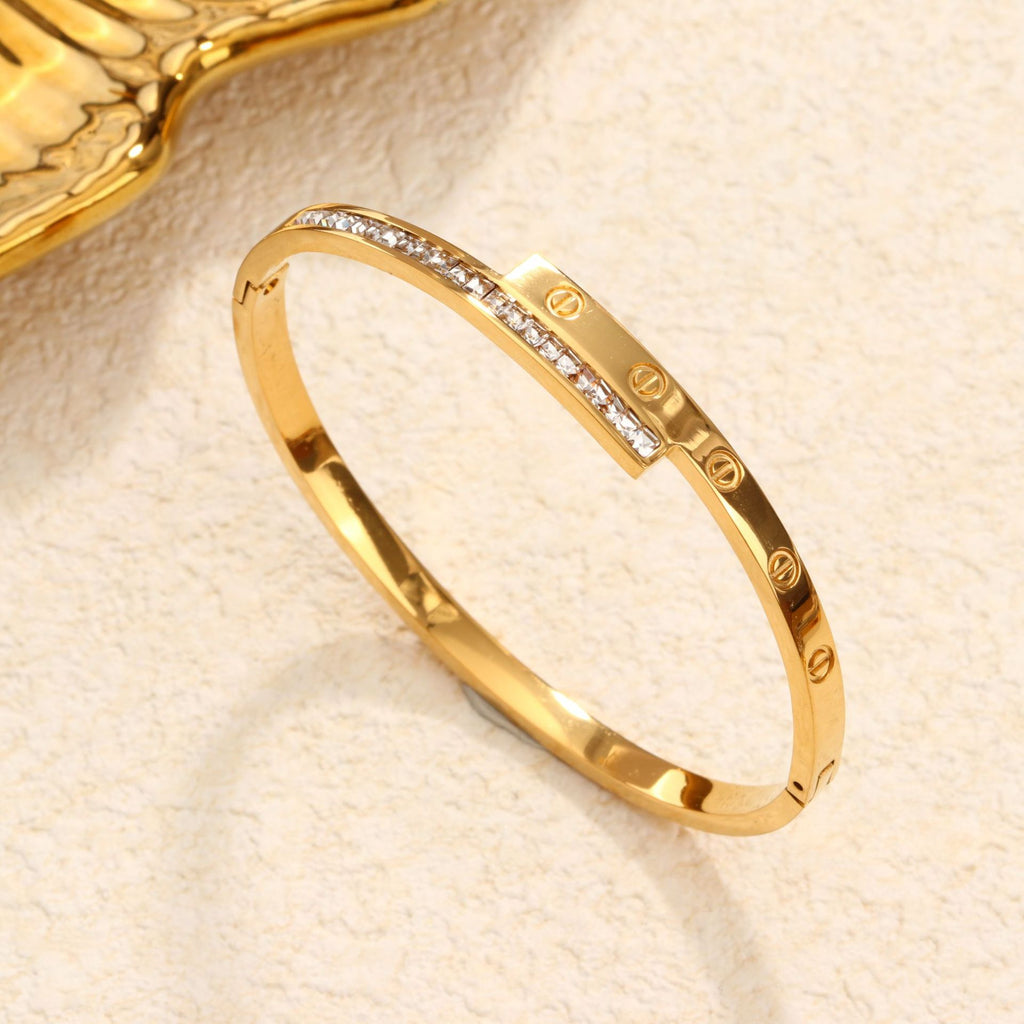 Engraved screw motif and channel-set cubic zirconia T-bar hinged cuff bangle in waterproof 18k gold plated stainless steel jewelry.