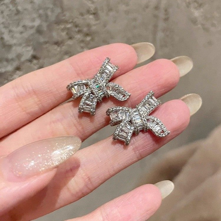 Silver bowknot stud earrings featuring a delicate ribbon design fully set with sparkling clear zirconia stones
