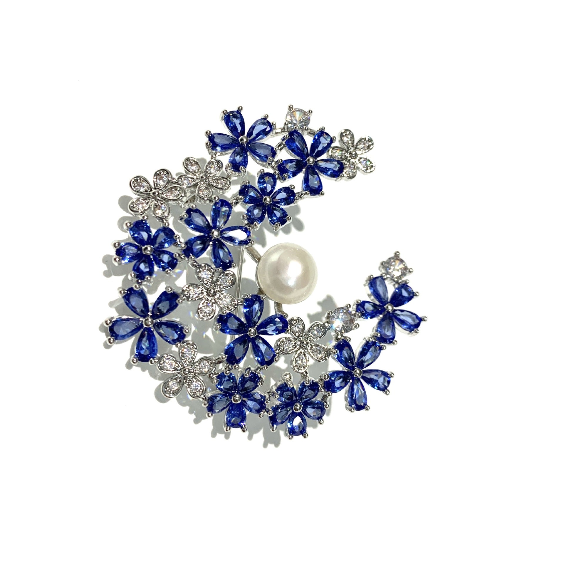Silver crescent moon brooch featuring blue and white cubic zirconia with a lustrous white pearl accent