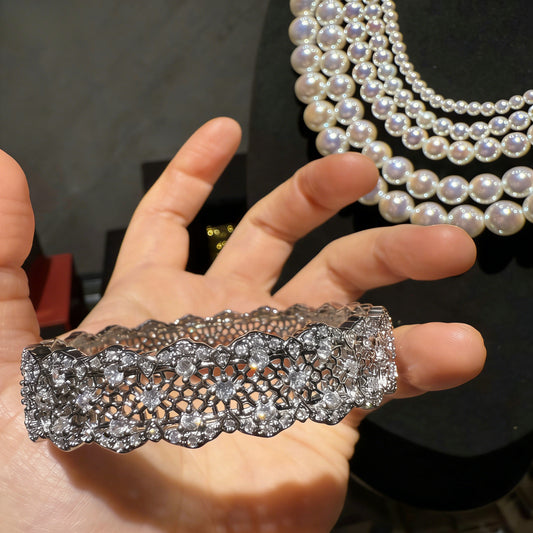 Elegant silver bangle with an intricate lace-inspired cutout pattern and sparkling white cubic zirconia