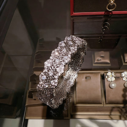 Elegant silver bangle with an intricate lace-inspired cutout pattern and sparkling white cubic zirconia