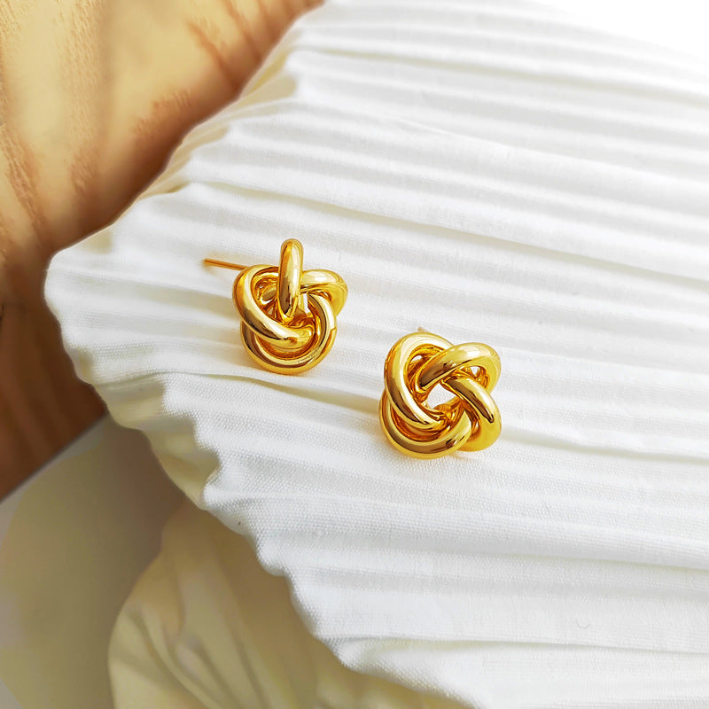 Bold gold multi-strand interwoven love knot stud earrings with hollow woven texture.
