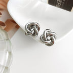 Bold gold multi-strand interwoven love knot stud earrings with hollow woven texture.