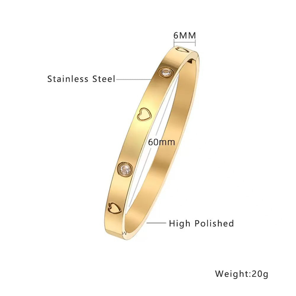 Engraved heart and bezel-set cubic zirconia hinged cuff bangle in waterproof 18k gold plated stainless steel jewelry.