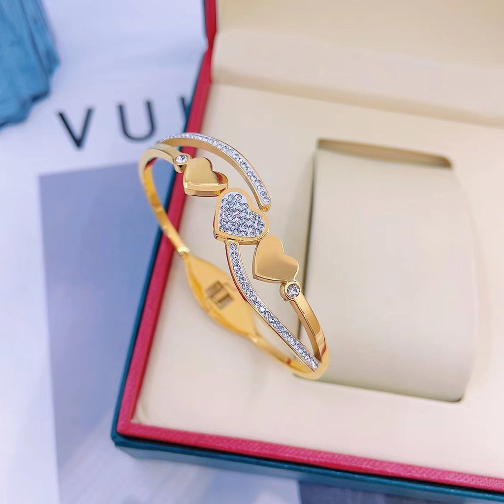 Triple heart station and pave cubic zirconia accent hinged cuff bangle in waterproof 18k gold plated stainless steel jewelry.