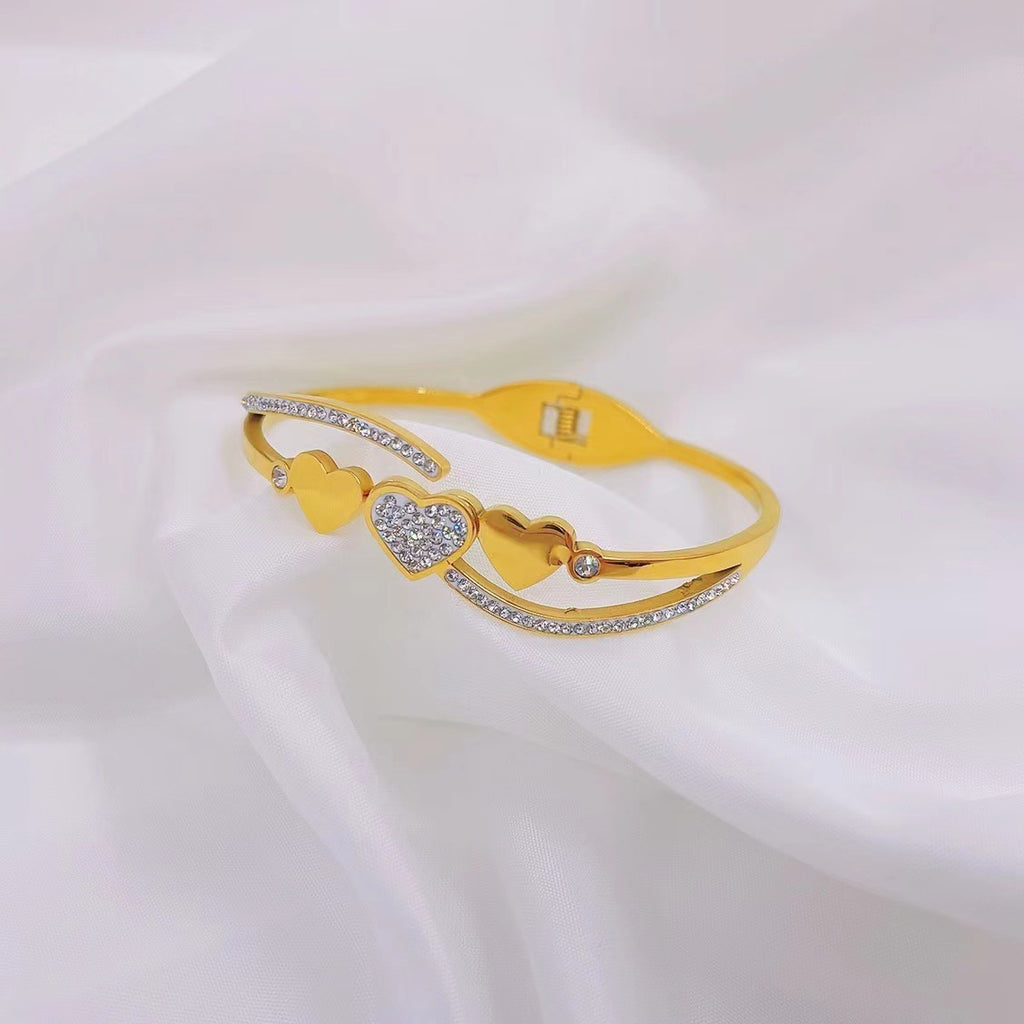Triple heart station and pave cubic zirconia accent hinged cuff bangle in waterproof 18k gold plated stainless steel jewelry.