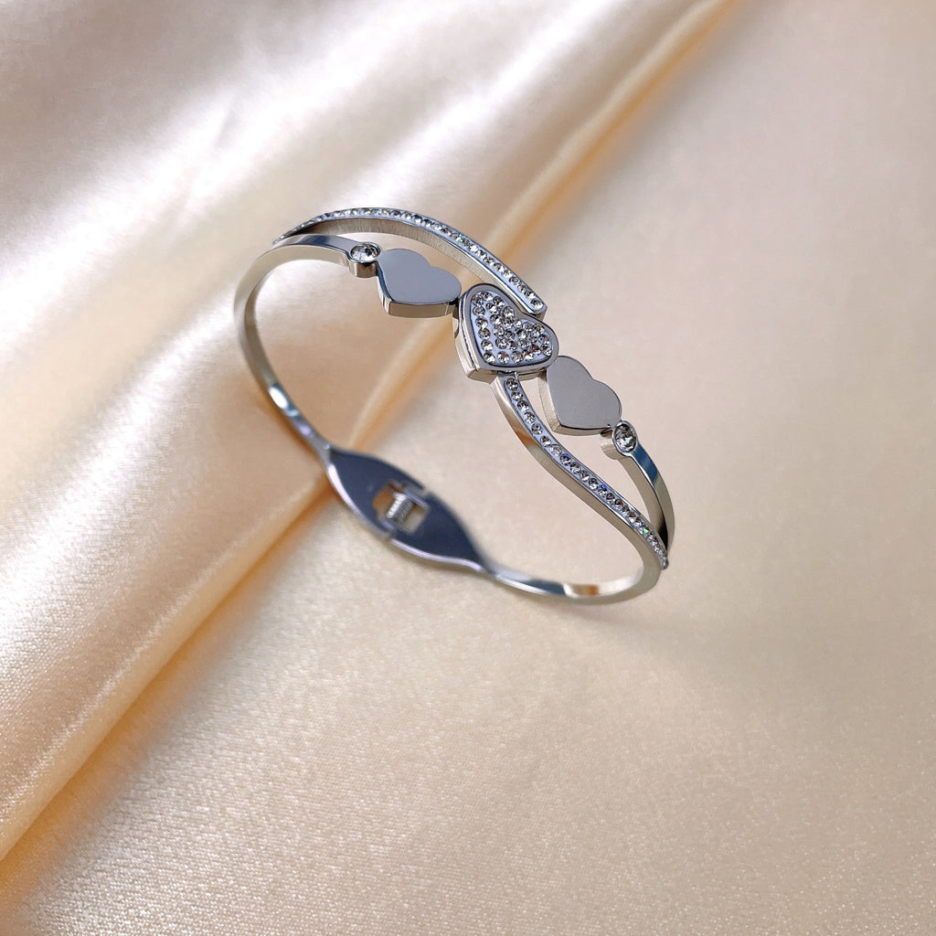 Triple heart station and pave cubic zirconia accent hinged cuff bangle in waterproof 18k gold plated stainless steel jewelry.