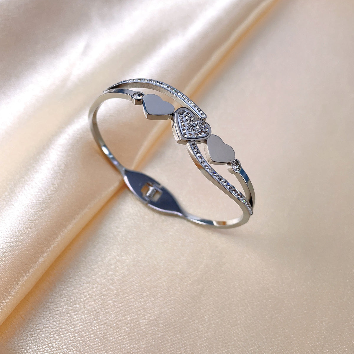 Triple heart station and pave cubic zirconia accent hinged cuff bangle in waterproof 18k gold plated stainless steel jewelry.