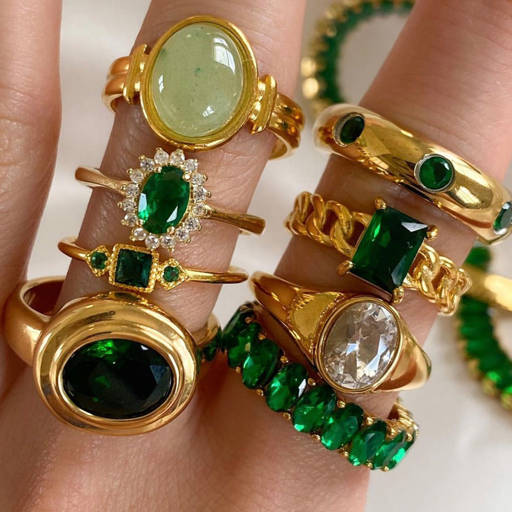 Oval emerald green cubic zirconia center stone framed by a sparkling clear cz crystal halo stainless steel jewelry ring in waterproof 18k gold plated finish.