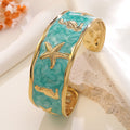 Wholesale stainless steel jewelry low MOQ 304 stainless steel gold enamel cuff bangle bracelet with starfish and seahorse motifs.
